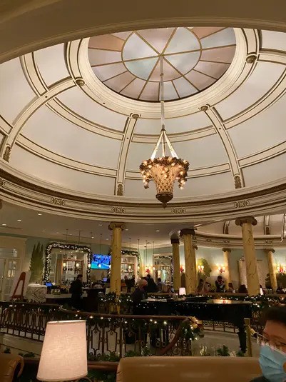 A view looking up at the high, ornate domed ceiling and large chandelier of the Laurel Court dining area, with columns and holiday decor visible around the lower level.
