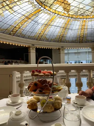 A tiered platter of scones, sandwiches, and pastries for afternoon tea, set beneath the magnificent stained-glass dome of The Rotunda at Neiman Marcus