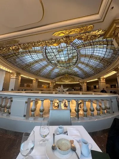 A close-up view of the intricate stained-glass dome ceiling and the balcony railing of The Rotunda at Neiman Marcus, featuring a large white decorative star