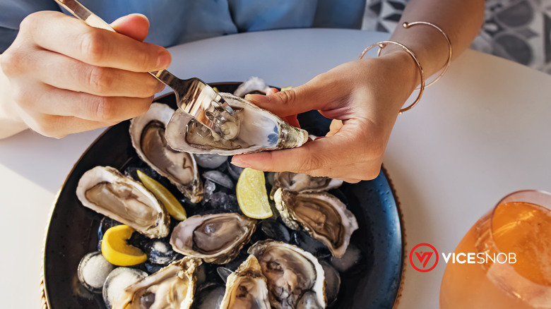Woman eating fresh oysters with lemon close-up.