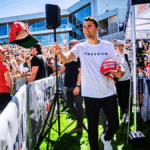 Charlie Kirk handed out red MAGA hats to a cheering crowd at an outdoor rally.