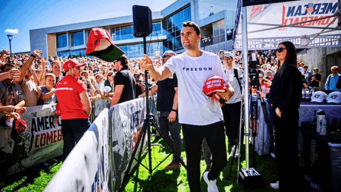 Charlie Kirk handed out red MAGA hats to a cheering crowd at an outdoor rally.