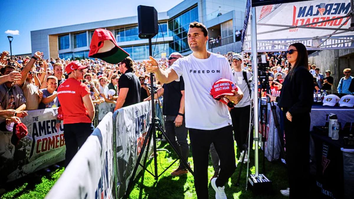 Charlie Kirk handed out red MAGA hats to a cheering crowd at an outdoor rally.