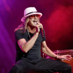 Kid Rock singing passionately on stage during a live concert performance.