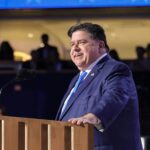 Illinois Governor JB Pritzker speaks at a podium during a public event, featured in JB Pritzker News coverage.