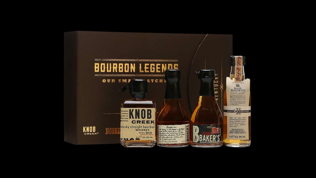 A dark brown gift box set labeled "BOURBON LEGENDS" and "OUR SMALL BATCHES" is shown with four miniature bottles of bourbon standing in front of it: Knob Creek, Booker's, Baker's, and Basil Hayden's. The image is shot against a solid black background.