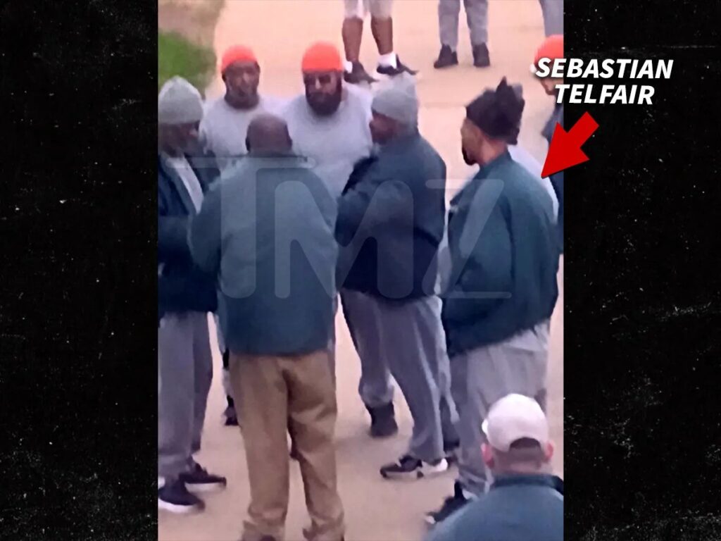 A grainy photo of Sebastian Telfair, identified by a red arrow and text, standing in a group of men wearing prison attire, linking up behind bars. The scene relates to the P Diddy prison twist story.