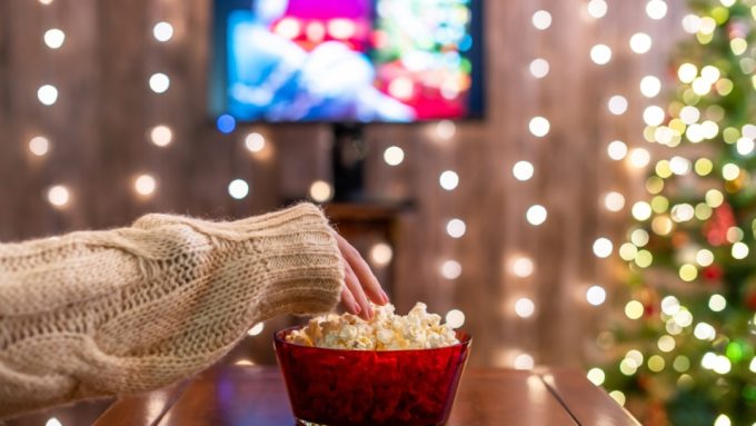 a hand on popcorn depicting Top 10 Christmas movies on Netflix poster image, promoting the best holiday movies on Netflix for 2025.