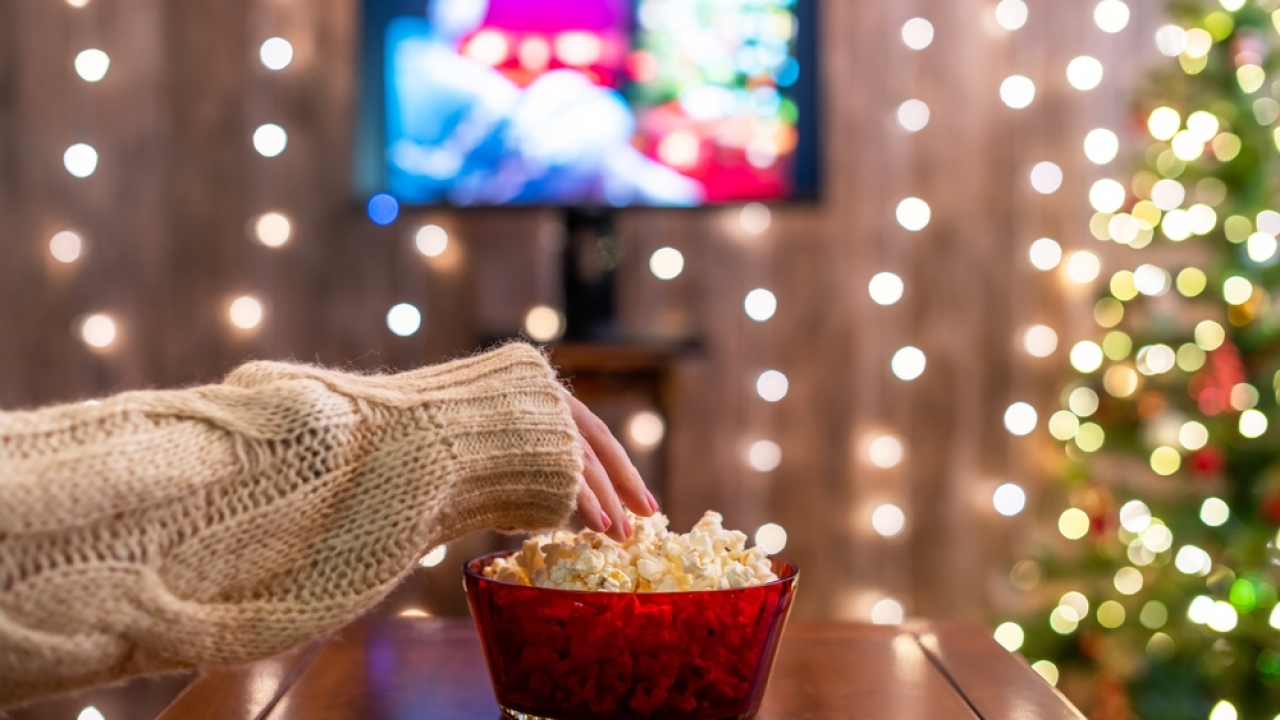 a hand on popcorn depicting Top 10 Christmas movies on Netflix poster image, promoting the best holiday movies on Netflix for 2025.