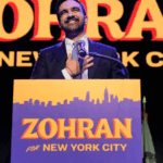 A dynamic photo of Zohran Mamdani raising his fist in celebration against a backdrop of supporters, symbolizing his major political victory to become Zohran Mamdani NYC Mayor