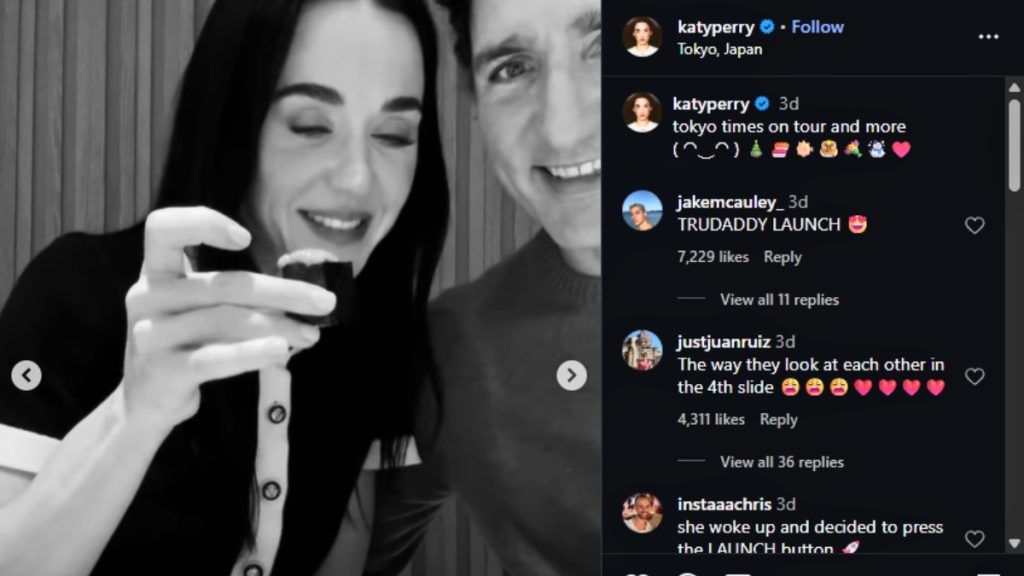 A black and white close-up shot of two people, one appearing to be Katy Perry, smiling and winking while holding a piece of food, and the other appearing to be Justin Trudeau, smiling next to her.