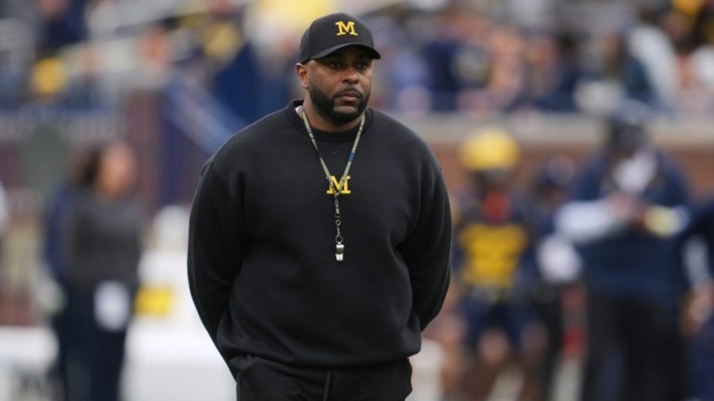 Sherrone Moore Suspended—a headline graphic discussing the coach's inappropriate relationship, firing, and subsequent arrest.