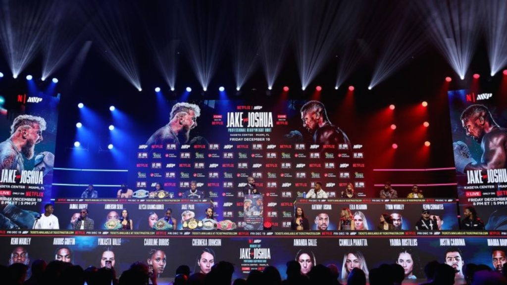 A high-energy promotional poster for the Jake Paul vs Anthony Joshua Netflix special, highlighting the "Big Stage Moment" at the Kaseya Center in Miami.