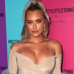 Influencer Anastasia Karanikolaou posing at a PrettyLittleThing event wearing a neutral off-the-shoulder top.