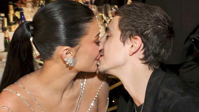 A candid, close-up profile shot of Timothée Chalamet and Kylie Jenner sharing a kiss while seated at a formal event.