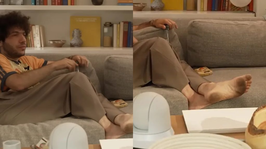 A side-by-side comparison of two screenshots from a podcast. The left frame shows record producer Benny Blanco sitting on a grey couch in a casual orange shirt and tan trousers, looking toward the interviewer. The right frame is a zoomed-in shot of the same scene, focusing on Blanco’s bare feet resting on the edge of the couch; the soles of his feet appear visibly dirty.