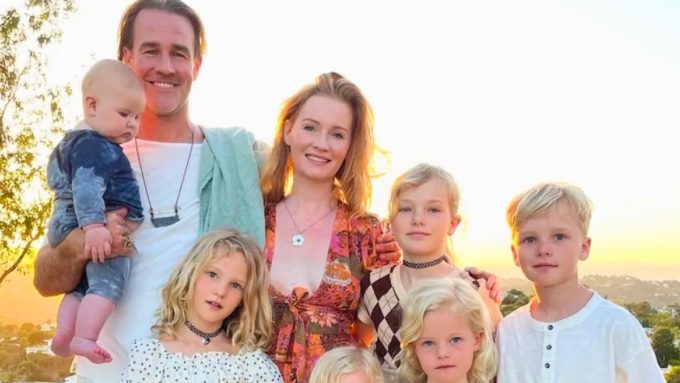 A warm family photo of James Van Der Beek, his wife Kimberly, and their six children posing outdoors under large oak trees. James is smiling while one daughter sits on his shoulders. The image is associated with news regarding a James Van Der Beek GoFundMe and the family’s move to a $4.76M ranch in Texas.