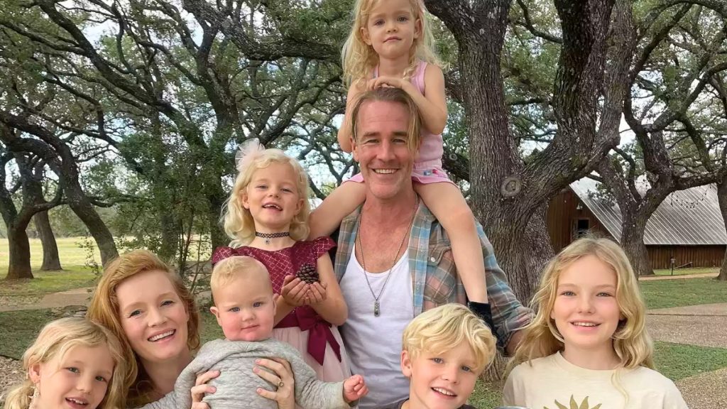 A portrait of James Van Der Beek and his family standing together at sunset with a scenic valley in the background. James holds their youngest child while the rest of the family poses closely together. This photo appears in coverage discussing the James Van Der Beek GoFundMe and his final Texas ranch real estate deal.