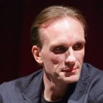 A thumbnail for a video titled "Peter Greene Cause of Death: Accidental Gunshot Revealed." The image features a large, somber headshot of Peter Greene. Next to him is an illustrative graphic of a human torso with a highlight on the "left axilla" (armpit area) where the medical examiner confirmed the fatal wound occurred.