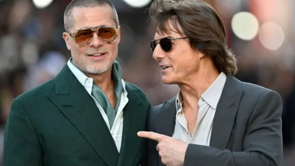 A realistic AI-generated image of Brad Pitt and Tom Cruise standing side-by-side. Brad Pitt is on the left wearing a green blazer, a light green scarf, and amber-tinted aviator sunglasses with a buzz cut. Tom Cruise is on the right, pointing toward Pitt while wearing a dark grey suit and classic black sunglasses with his hair styled in a longer, feathered look.
