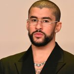 Bad Bunny birthday celebration portrait featuring Benito in a sleek black suit, silver rimless glasses, and a diamond chain.