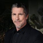 Actor Christian Bale posing at a red carpet event, frequently cited in discussions regarding his reaction to the performance of Jacob Elordi Frankenstein. He is wearing a black dress shirt and suit jacket.