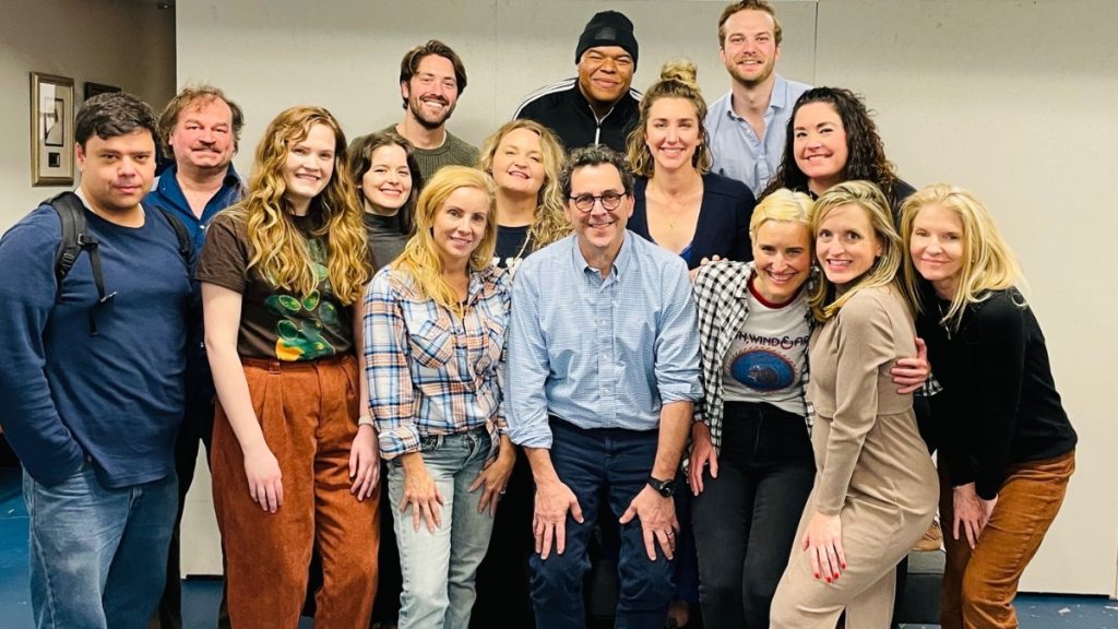 A group photo featuring Corey Parker in a light blue button-down shirt, surrounded by a diverse group of his students and colleagues in an acting studio setting.