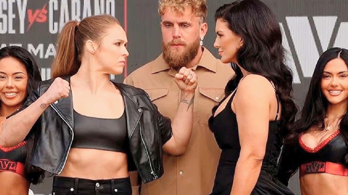 MMA legends Gina Carano and Ronda Rousey face off at the Intuit Dome press conference for their 2026 Netflix fight night. Gina Carano (right) and Ronda Rousey (left) stand on either side of Jake Paul during the Most Valuable Promotions event.