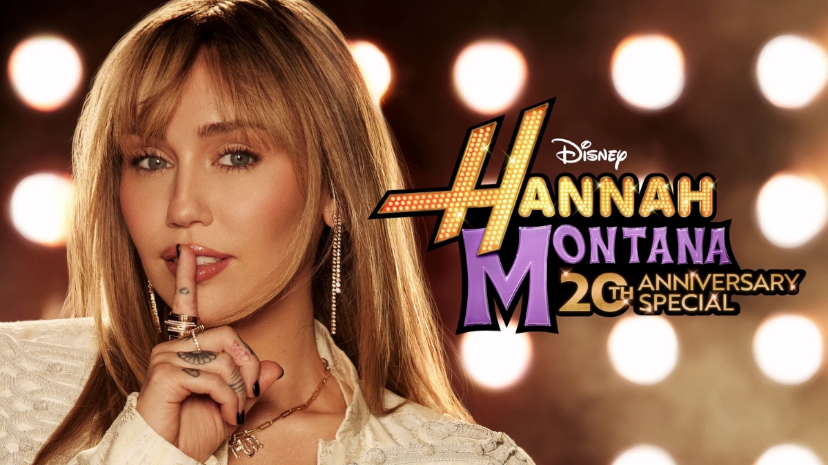 A promotional graphic for the Hannah Montana 20th Anniversary Special featuring a close-up of Miley Cyrus holding a finger to her lips in a "shushing" gesture; the official Disney logo and anniversary title are displayed prominently against a backdrop of warm, blurred stage lights.