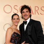 A heartwarming portrait of Jacob Elordi and his mother, Melissa, on the Oscars red carpet. Jacob wears a sleek tuxedo, and Melissa is in a sequined gown, both beaming for the cameras.