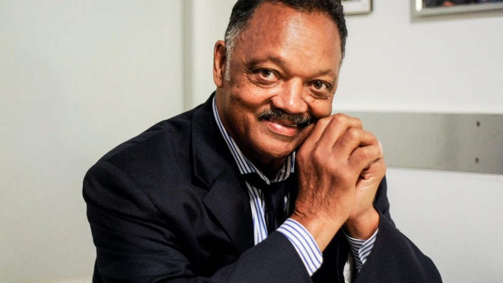 A portrait of Reverend Jesse Jackson smiling with his hands clasped, illustrating the legacy celebrated at the Jesse Jackson Funeral following his long battle with Progressive Supranuclear Palsy (PSP).