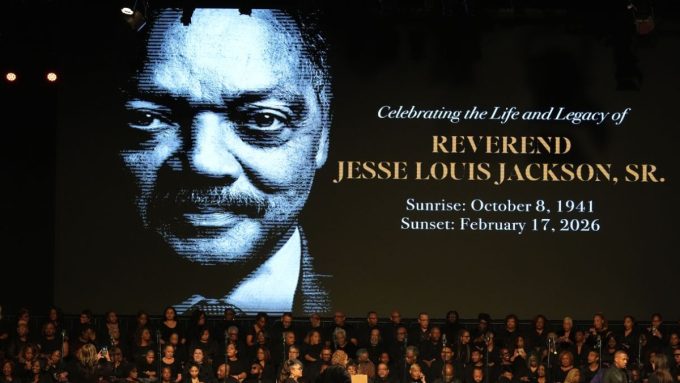 A large commemorative screen displays a portrait of Reverend Jesse Louis Jackson, Sr., noting his birth on October 8, 1941, and his passing on February 17, 2026, as a choir gathers for the Jesse Jackson Funeral.