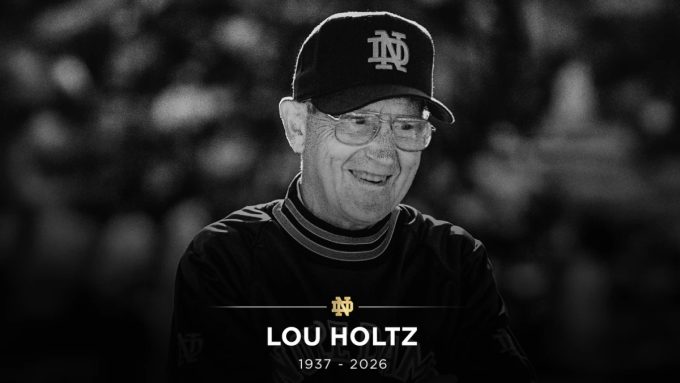 A black-and-white memorial tribute image of Lou Holtz wearing a Notre Dame cap and pullover. The bottom of the image features a gold Notre Dame "ND" logo above the text "LOU HOLTZ 1937 - 2026