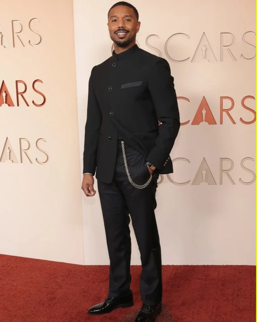 Michael B. Jordan  wearing a textured charcoal grey tuxedo with a silk turtleneck underneath.