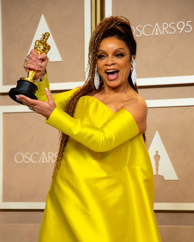 Legendary costume designer Ruth E. Carter wearing a vibrant, architectural ensemble featuring bold patterns and structured gold accessories.