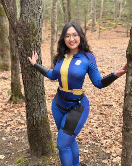 Arrum Kim in a blue and yellow vault suit posing in a forest