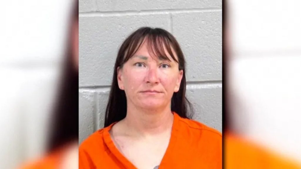A close-up mugshot of Jessica McClure Morales. She is facing forward with a somber expression, featuring dark hair, bangs, and light-colored eyes. She is wearing a bright orange V-neck jumpsuit.