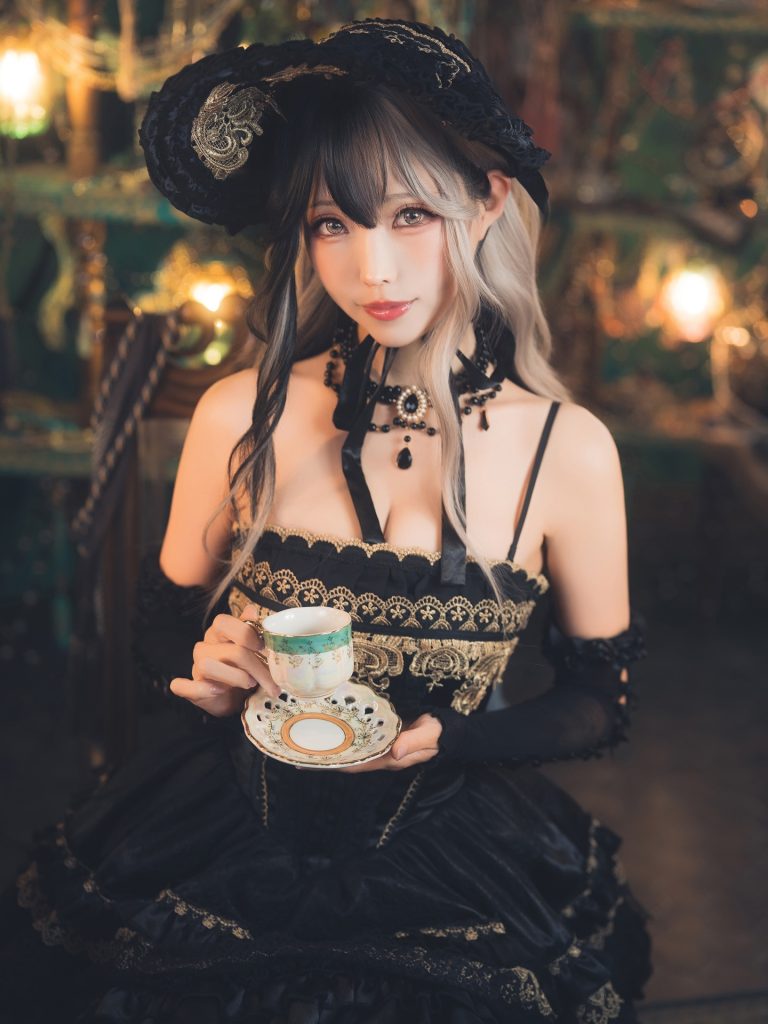 Ely Cosplay in a sleek, modern look wearing a form-fitting black sleeveless top with a high collar. She is looking slightly off-camera, highlighting her sharp features against a minimalist, bright background.