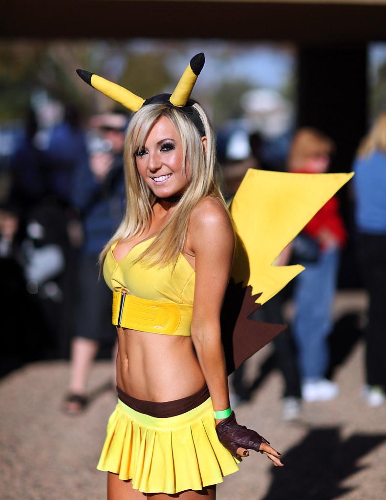 The viral "Sexy Pikachu" outfit that helped establish Jessica Nigri as one of the hottest female cosplayers in the industry. She is pictured at a convention in a bright yellow crop top and pleated skirt, complete with Pikachu ears and a lightning-bolt tail. The sunlit outdoor setting shows her smiling at the camera with her signature blonde hair.