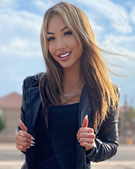Kiara Moon smiling in a black leather jacket outdoors.