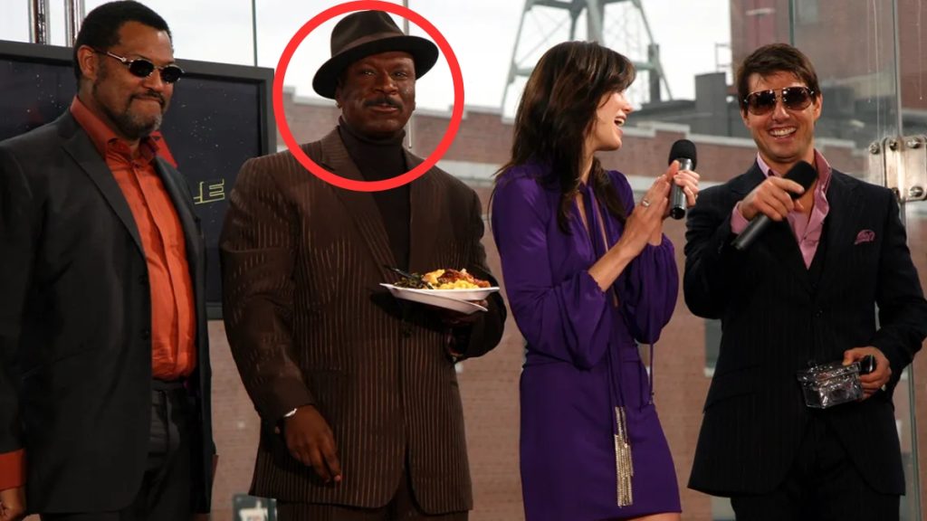 Ving Rhames at a celebrity press event, dressed in a black turtleneck and pinstripe blazer with a wide-brimmed hat.