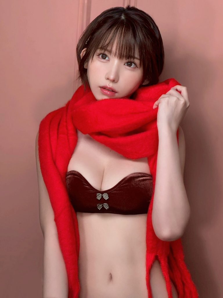 Enako looking back over her shoulder while standing in a doorway. She is wearing a beige lace lingerie set with a grey velvet skirt or garment partially pulled down, set against a granite-tiled wall.
