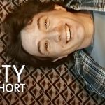 A smiling young Martin Short lying on a patterned carpet while wearing a plaid shirt, featuring the overlaid text "MARTY LIFE IS SHORT."