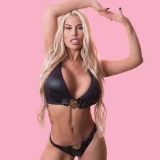 Bridgette B millf onyfans posed against pink wall in black leather bikini