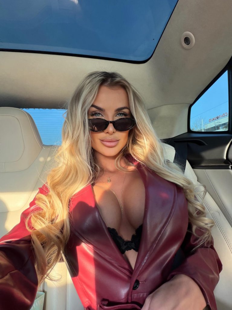 Denisa Gottvaldová, known as a top Czech OnlyFans influencer, sitting inside a car while wearing a red leather jacket and sunglasses.