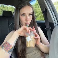 Leila Babyxo, an influential Irish OnlyFans model, drinking an iced coffee while relaxing in the passenger seat of a car.