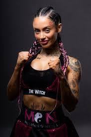 Irish OnlyFans and content creator Meghan O'Neill, known as Skye Fox, in a boxing stance wearing a sports bra labeled "The Witch" with her hair in tight braids.