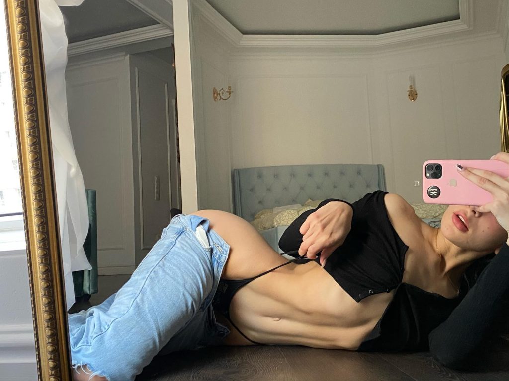 Dutch Onlyfans star Ellie Leen captured in a casual mirror selfie wearing a light-colored top