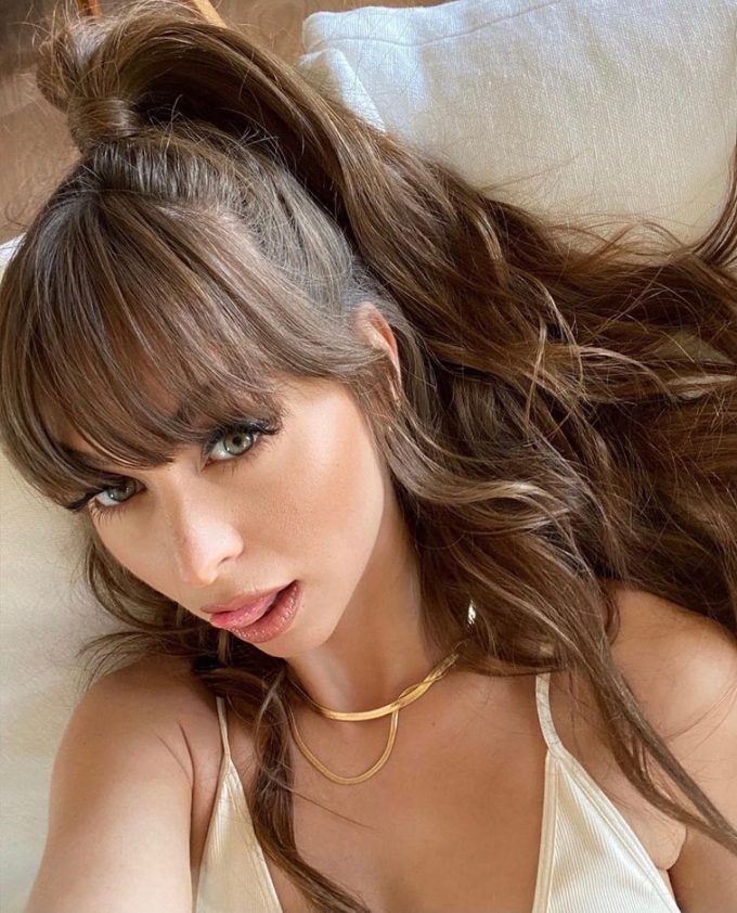 A close-up portrait of content creator Riley Reid looking at the camera with her hair in a high ponytail and bangs, perfect for a Riley Reid OnlyFans biography update.