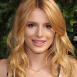 A portrait shot of Bella Thorne with wavy blonde hair, wearing a "BG" initial necklace.